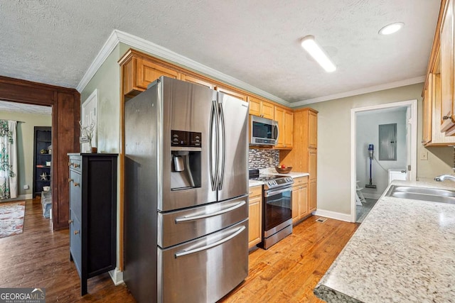 kitchen with a sink, stainless steel appliances, electric panel, ornamental molding, and a textured ceiling