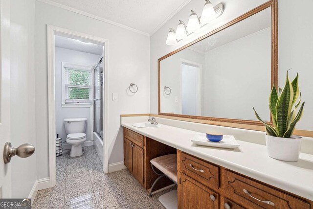 bathroom featuring ornamental molding, an enclosed shower, toilet, vanity, and baseboards