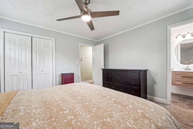 carpeted bedroom with a closet, a ceiling fan, baseboards, ornamental molding, and ensuite bathroom