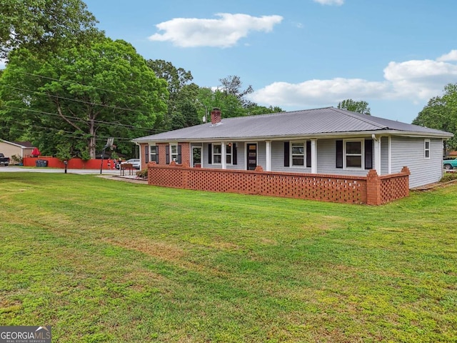 ranch-style house featuring covered porch, metal roof, a front yard, and a chimney