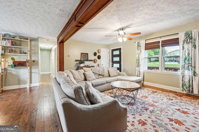 living room with hardwood / wood-style floors, baseboards, visible vents, a ceiling fan, and a textured ceiling