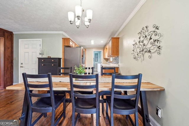 dining room with ornamental molding, dark wood-style floors, a textured ceiling, and an inviting chandelier