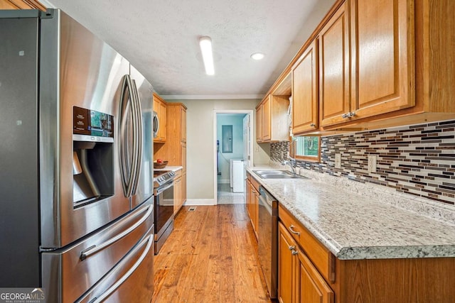 kitchen with decorative backsplash, a sink, light wood-style floors, stainless steel appliances, and baseboards