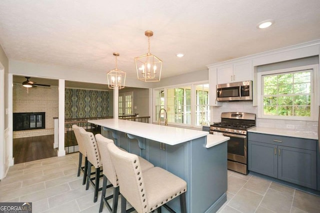 kitchen with appliances with stainless steel finishes, light tile patterned floors, light countertops, and a kitchen breakfast bar