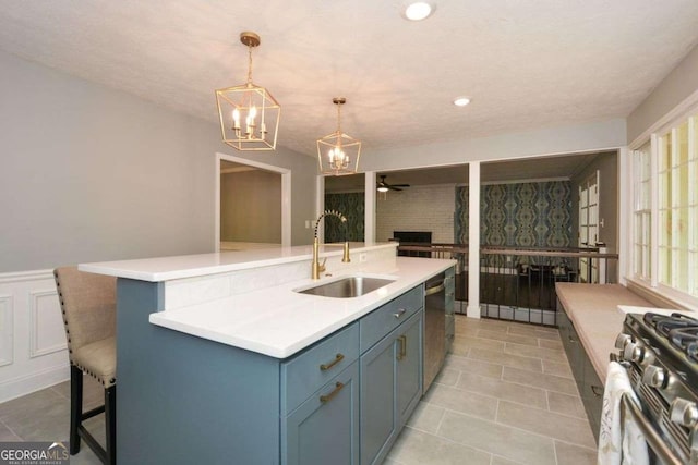 kitchen with a kitchen island with sink, appliances with stainless steel finishes, light countertops, ceiling fan with notable chandelier, and a sink