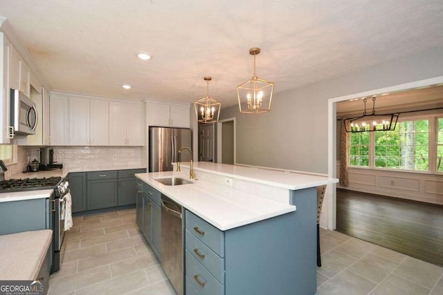 kitchen with stainless steel appliances, backsplash, a sink, white cabinetry, and a notable chandelier