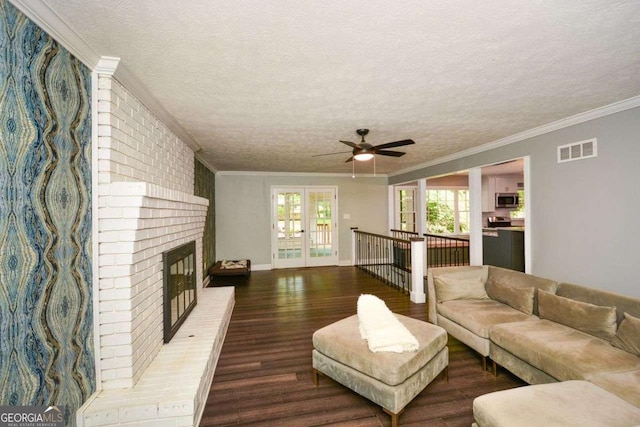 living room featuring a ceiling fan, visible vents, wood finished floors, and a textured ceiling
