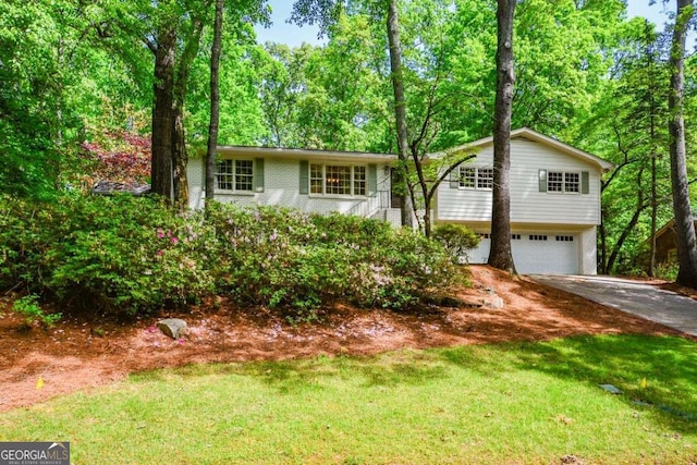 view of front of property featuring concrete driveway, a front lawn, an attached garage, and brick siding