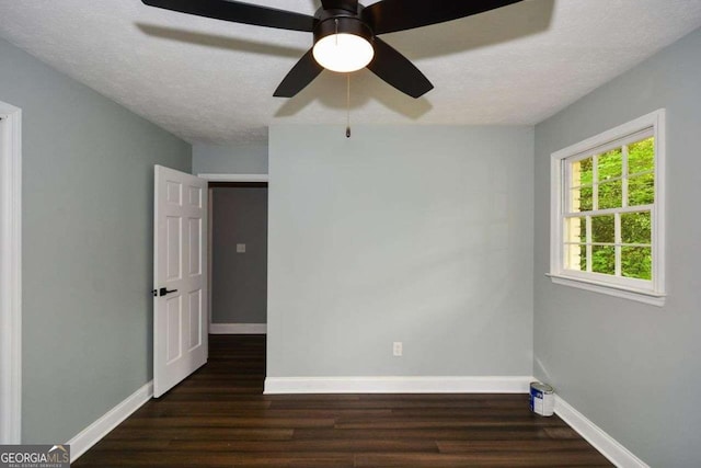 spare room featuring a textured ceiling, a ceiling fan, baseboards, and dark wood-type flooring