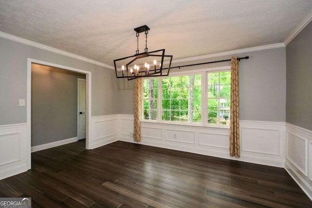 unfurnished dining area featuring a chandelier, ornamental molding, dark wood finished floors, a decorative wall, and wainscoting