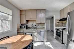 1824 Guardian Way, Lawrenceville, GA 30043 - kitchen with tasteful backsplash, gray cabinetry, stainless steel appliances, light countertops, and under cabinet range hood