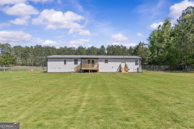 rear view of house with a deck, a yard, stairway, and fence