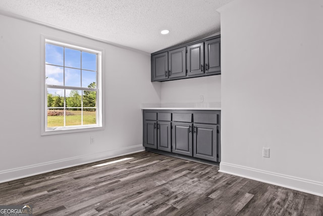 interior space featuring dark wood-style floors, baseboards, a textured ceiling, and recessed lighting