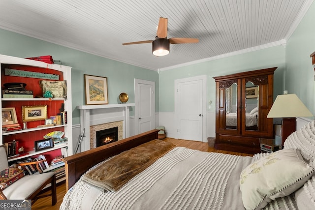 19 Oak Creek Cir, Toccoa, GA 30577 - bedroom with a wainscoted wall, a warm lit fireplace, ornamental molding, wood finished floors, and a ceiling fan