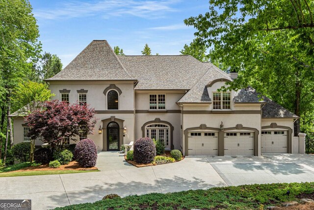 8345 Jett Ferry Rd, Sandy Springs, GA 30350 - french country style house with stucco siding, a garage, driveway, and roof with shingles