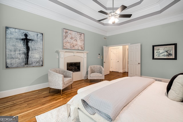 8345 Jett Ferry Rd, Sandy Springs, GA 30350 - bedroom featuring a raised ceiling, crown molding, a glass covered fireplace, wood finished floors, and ceiling fan