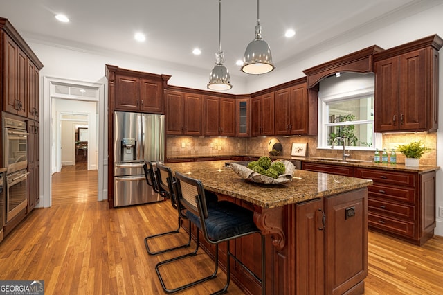 8345 Jett Ferry Rd, Sandy Springs, GA 30350 - kitchen with appliances with stainless steel finishes, light wood-type flooring, crown molding, a breakfast bar area, and a kitchen island
