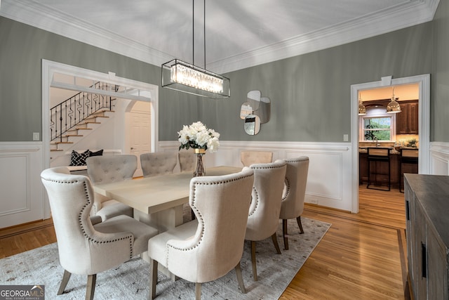 8345 Jett Ferry Rd, Sandy Springs, GA 30350 - dining area with stairs, a chandelier, ornamental molding, light wood finished floors, and a wainscoted wall