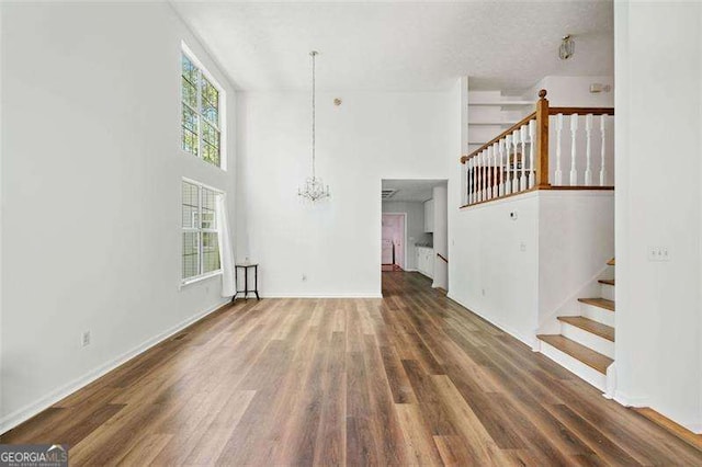 3420 Honeysuckle Ln, Lithia Springs, GA 30122 - unfurnished living room featuring wood finished floors, a notable chandelier, stairs, and a towering ceiling
