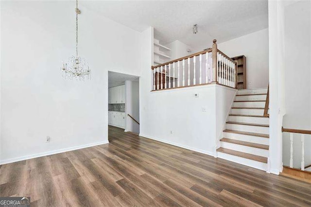 3420 Honeysuckle Ln, Lithia Springs, GA 30122 - unfurnished living room featuring wood finished floors, an inviting chandelier, stairs, baseboards, and a towering ceiling