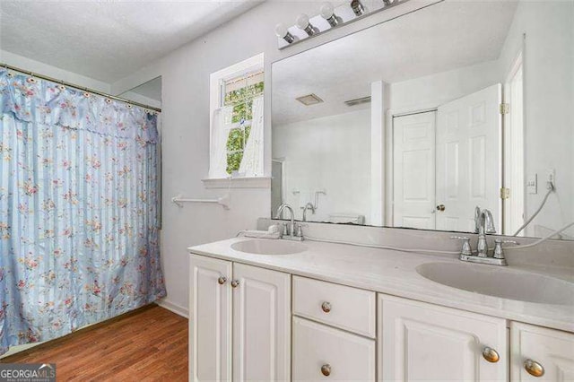 3420 Honeysuckle Ln, Lithia Springs, GA 30122 - bathroom with wood finished floors, a shower with shower curtain, double vanity, and a sink