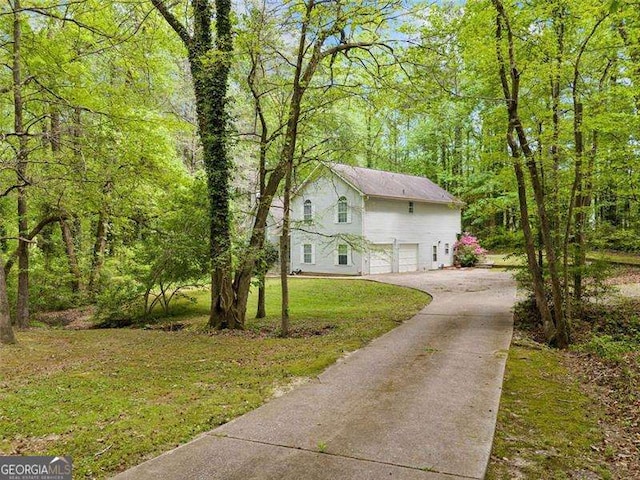 3420 Honeysuckle Ln, Lithia Springs, GA 30122 - view of side of property featuring a yard, an attached garage, a forest view, and aphalt driveway