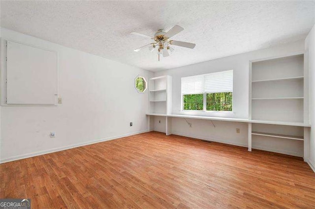 3420 Honeysuckle Ln, Lithia Springs, GA 30122 - empty room with a textured ceiling, ceiling fan, baseboards, wood finished floors, and built in features