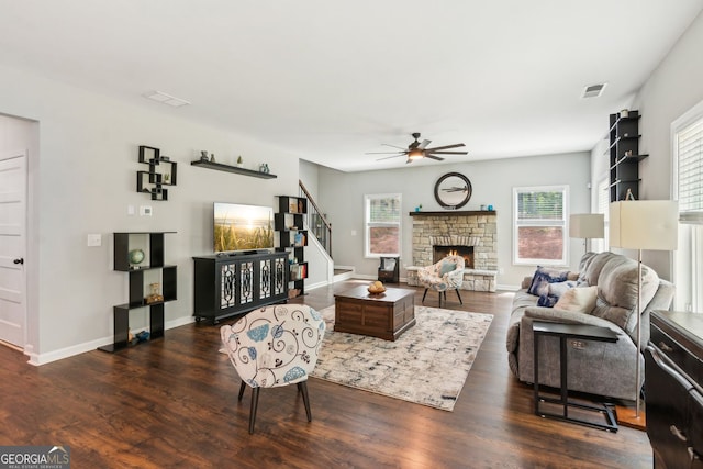 living area with dark wood-style floors, a ceiling fan, visible vents, and stairs