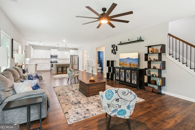living room featuring dark wood-style floors, stairs, ceiling fan, and baseboards