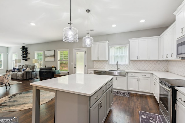 kitchen with stainless steel appliances, a kitchen island, light countertops, a sink, and gray cabinetry