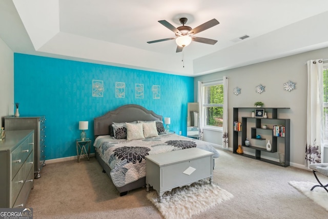 carpeted bedroom featuring visible vents, a raised ceiling, and baseboards