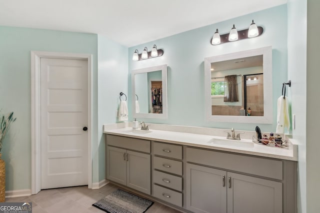 full bath featuring baseboards, tile patterned flooring, double vanity, and a sink