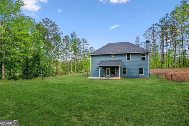 back of property with a lawn, fence, a chimney, and a patio