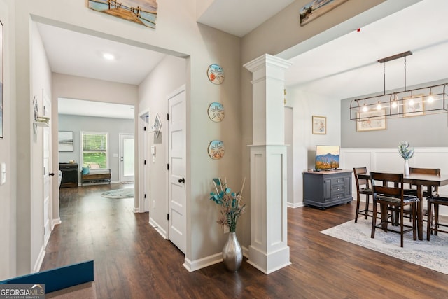 corridor featuring decorative columns and dark wood finished floors