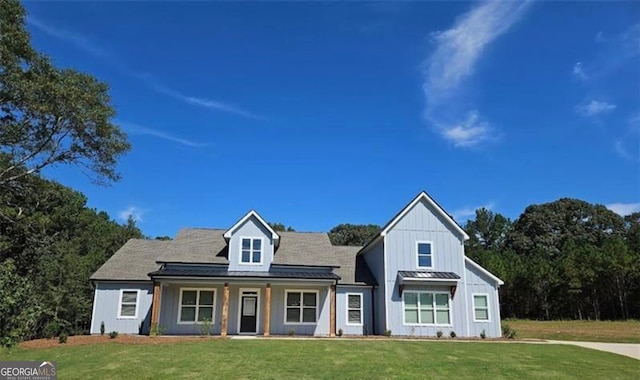 view of front facade featuring board and batten siding, a porch, a standing seam roof, metal roof, and a front lawn