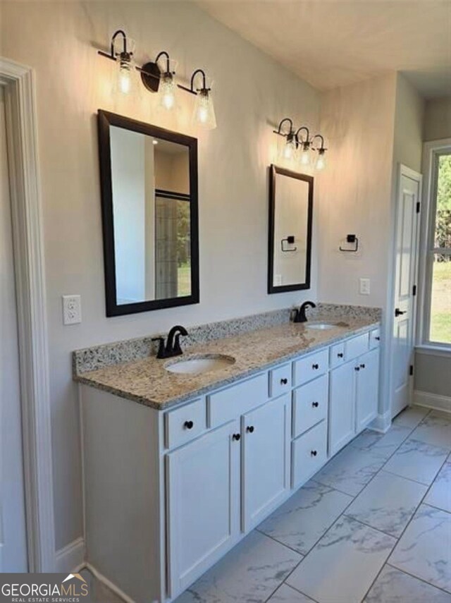bathroom featuring double vanity, baseboards, a sink, and marble finish floor