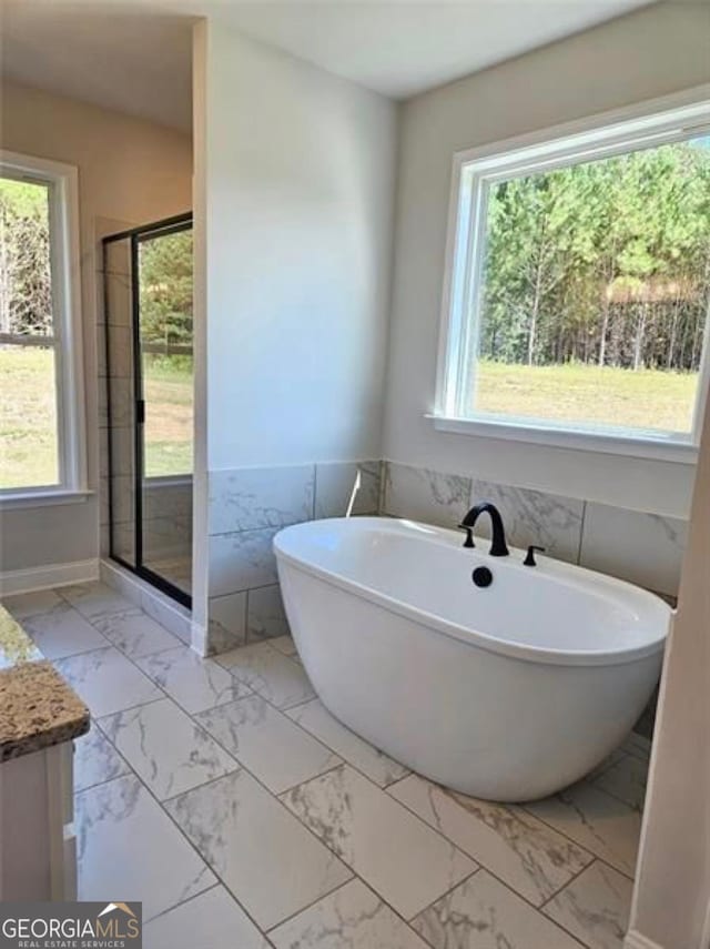 bathroom with vanity, a soaking tub, a stall shower, and marble finish floor
