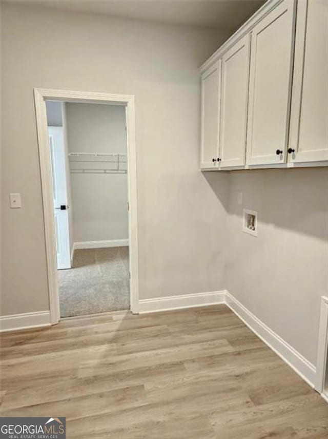 washroom with baseboards, hookup for a washing machine, cabinet space, and light wood finished floors