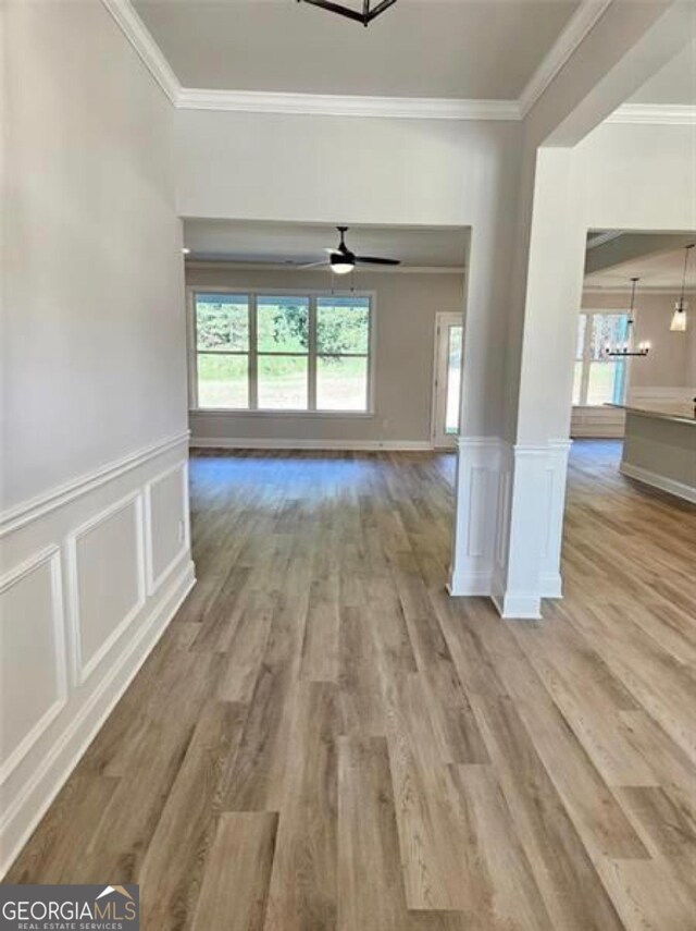 unfurnished living room with plenty of natural light, ornamental molding, and wood finished floors