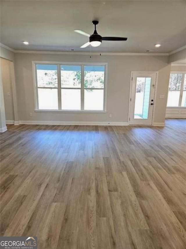 unfurnished living room with crown molding, baseboards, a ceiling fan, and wood finished floors