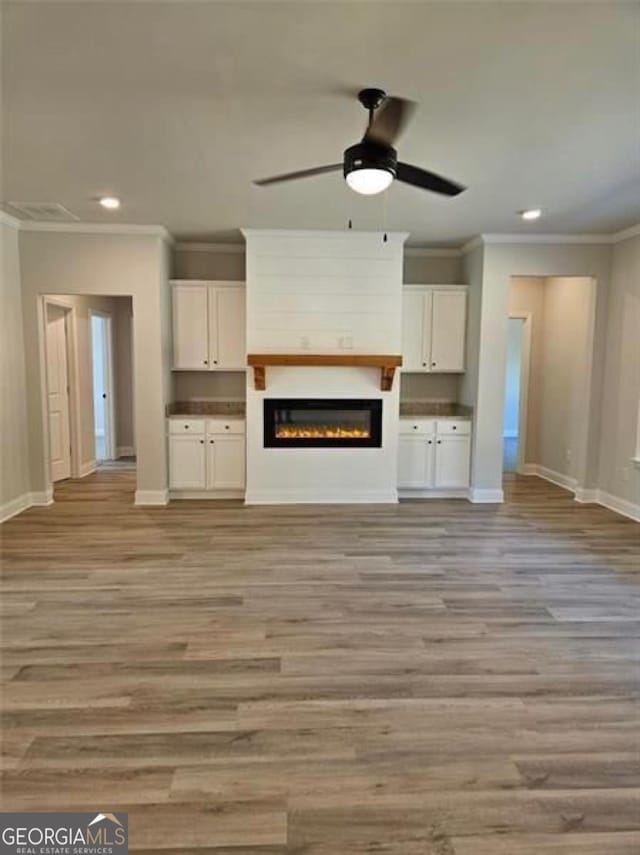 unfurnished living room featuring baseboards, ornamental molding, recessed lighting, and light wood-style flooring