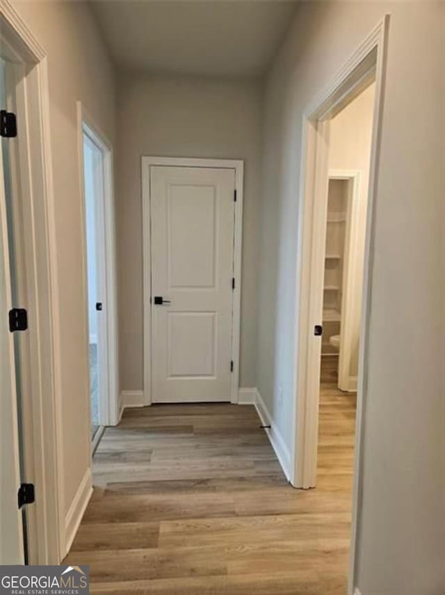 hallway with light wood-style floors and baseboards
