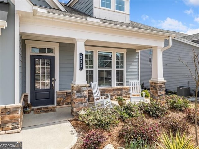 221 Hickory Bluffs Pkwy, Canton, GA 30114 - entrance to property featuring cooling unit, stone siding, a shingled roof, and covered porch