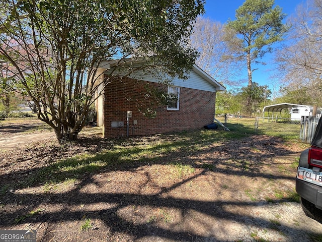 view of side of property with fence, a carport, and brick siding