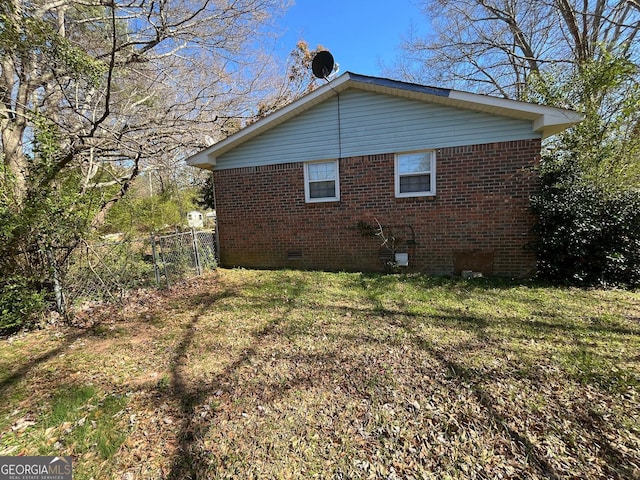 view of home's exterior with fence, a yard, crawl space, and brick siding