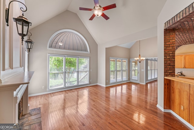 9255 Old Preserve Trl, Ball Ground, GA 30107 - unfurnished living room featuring ceiling fan, a chandelier, light wood-type flooring, and high vaulted ceiling
