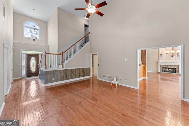 9255 Old Preserve Trl, Ball Ground, GA 30107 - foyer with a high ceiling, light wood-style flooring, a ceiling fan, a stone fireplace, and stairs