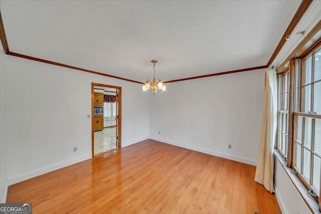 spare room featuring an inviting chandelier, a textured ceiling, light wood-type flooring, and crown molding