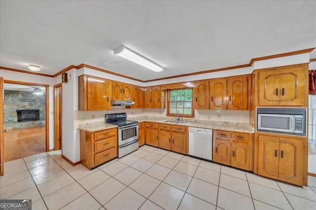 208 Earlwood Dr, Dublin, GA 31021 - kitchen with brown cabinets, crown molding, a sink, appliances with stainless steel finishes, and under cabinet range hood