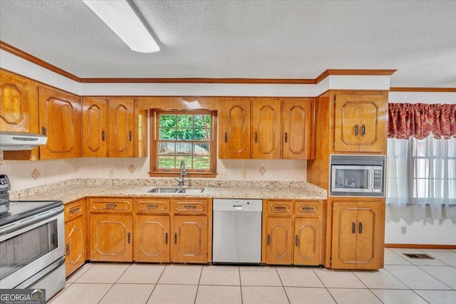 kitchen featuring brown cabinets, stainless steel appliances, under cabinet range hood, and a sink